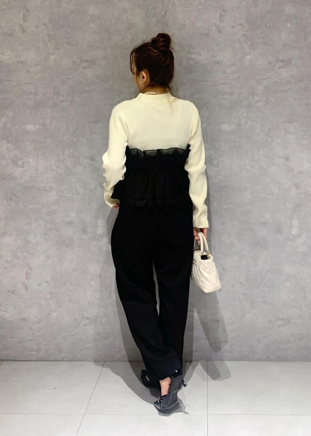 ブラック系のパンプス、ホワイト系のニット/セーター、ブラック系のスラックスを着用したレディースの冬コーディネートの5枚目の写真