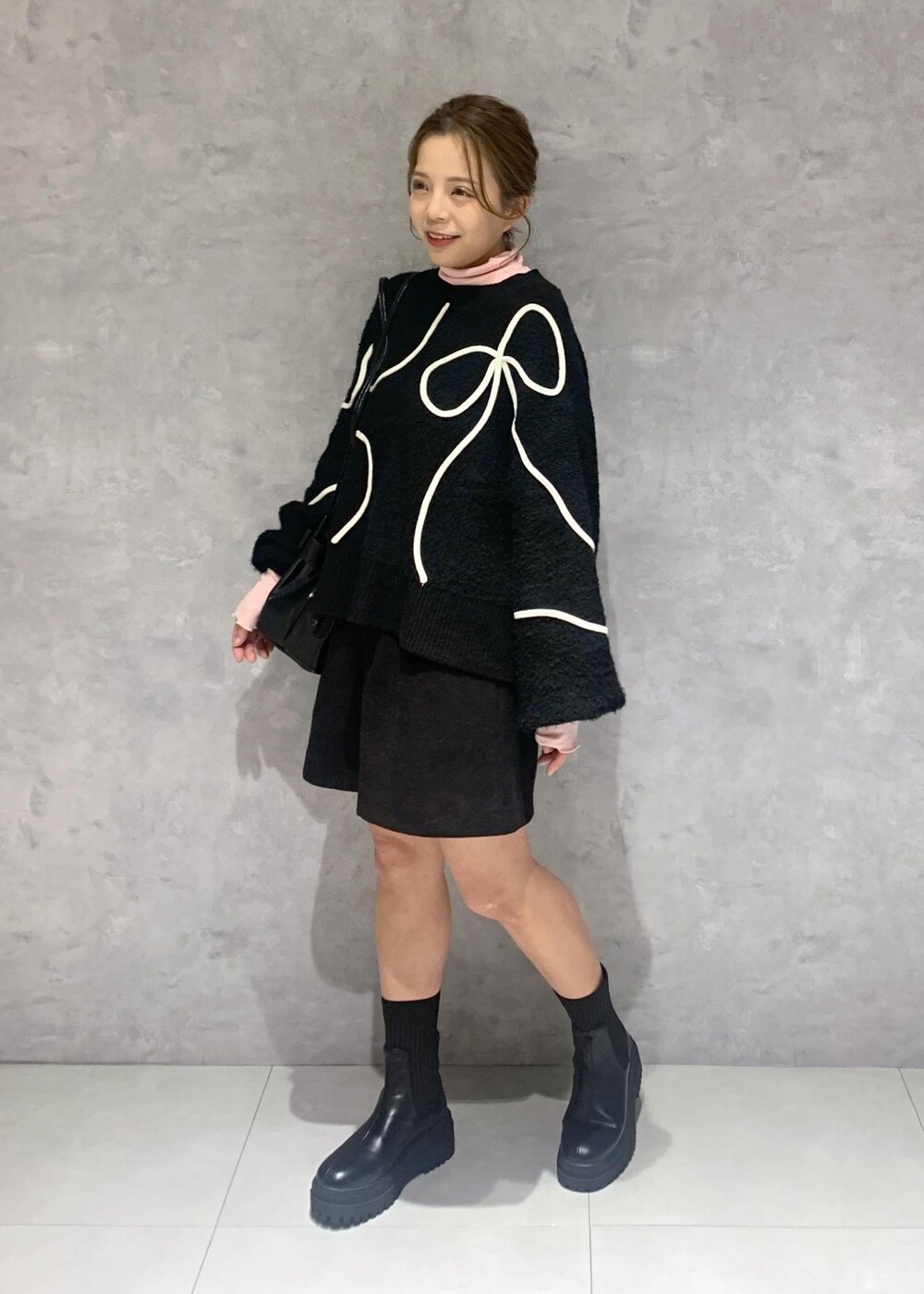 ブラック系のショルダーバッグ、ブラック系のブーツ、ブラック系のニット/セーターを着用したレディースの冬コーディネートの3枚目の写真