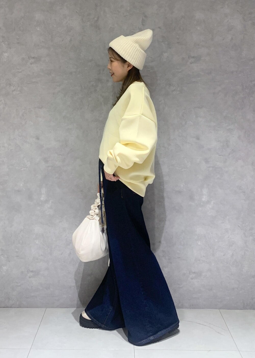 ブルー系のデニムパンツ、ホワイト系のブーツ、ホワイト系のショルダーバッグを着用したレディースの秋コーディネートの3枚目の写真