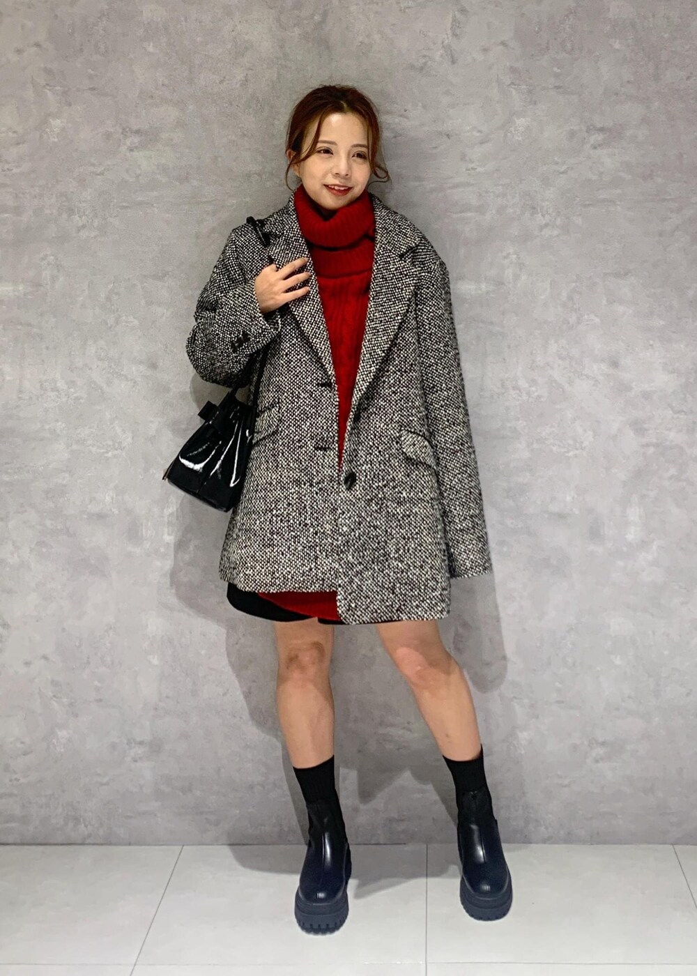 ブラック系のショルダーバッグ、ブラック系のブーツ、レッド系のワンピースを着用したレディースの冬コーディネートの3枚目の写真