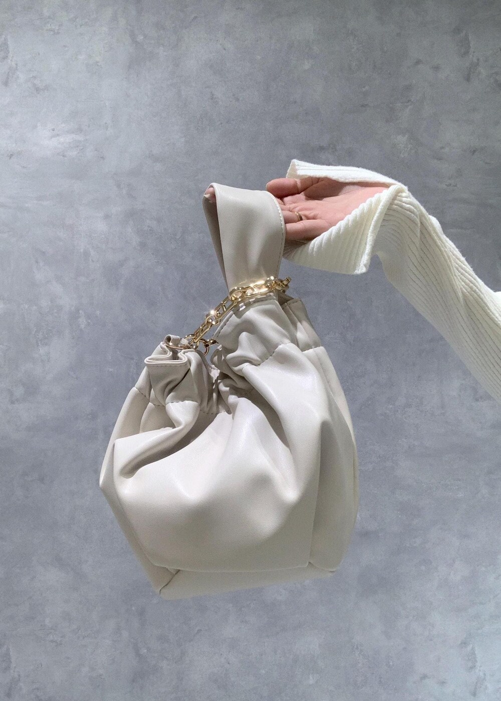 シルバー系のパンプス、ホワイト系のハンドバッグ、ホワイト系のニット/セーターを着用したレディースの冬コーディネートの9枚目の写真