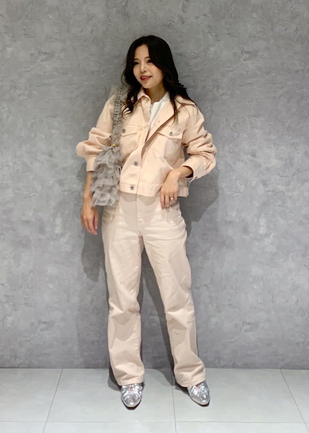 シルバー系のパンプス、ピンク系のデニムパンツ、ホワイト系のニット/セーターを着用したレディースの冬コーディネートの2枚目の写真