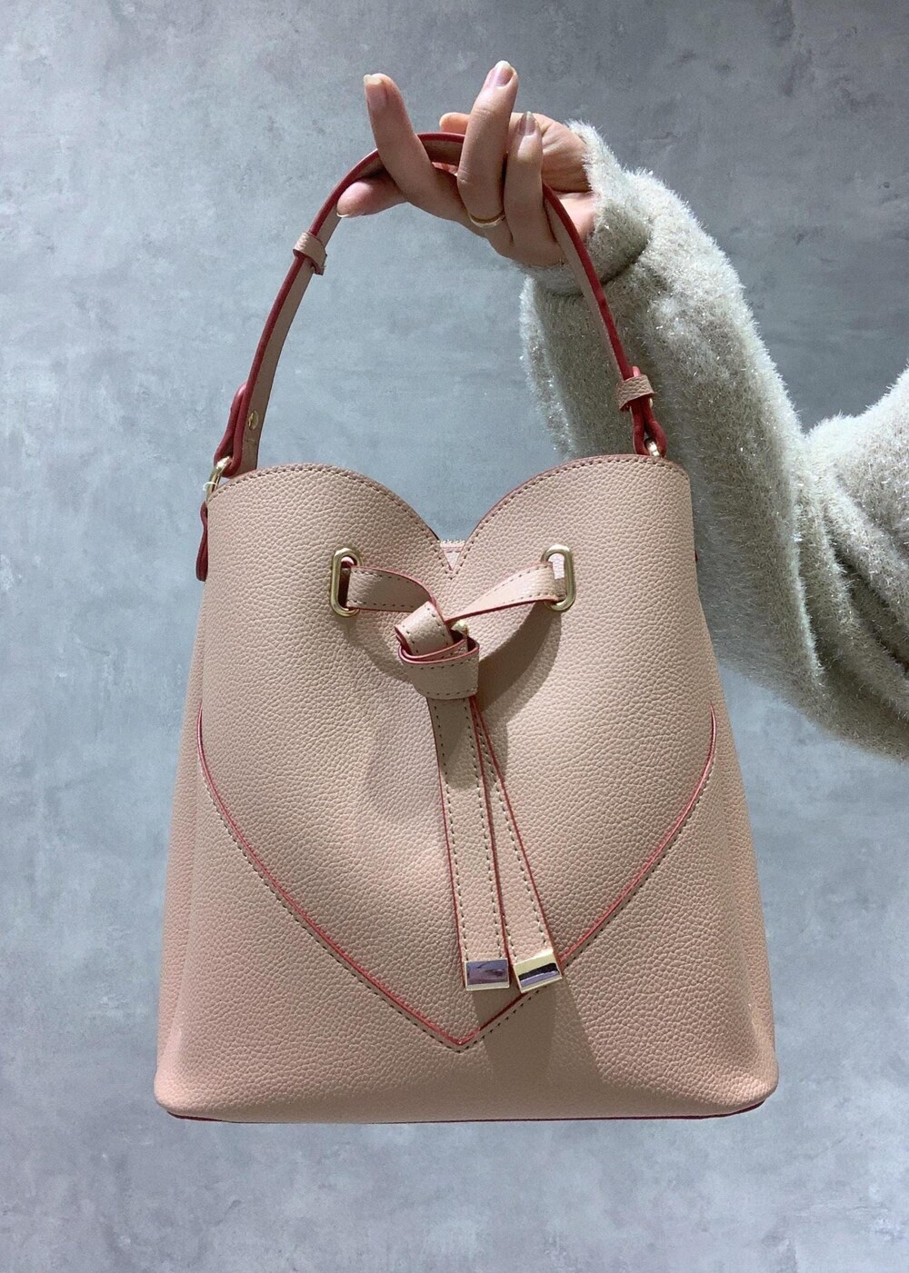 ピンク系のショルダーバッグ、ホワイト系のブーツ、ベージュ系のスカートを着用したレディースの冬コーディネートの9枚目の写真