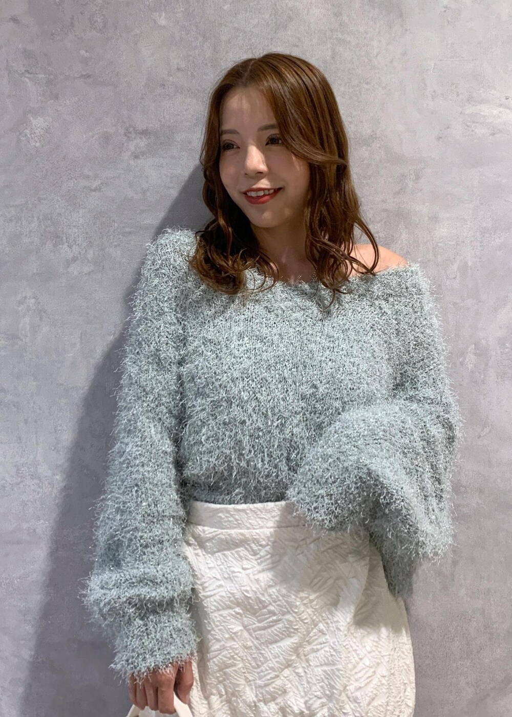 ホワイト系のブーツ、ホワイト系のスカート、グリーン系のニット/セーターを着用したレディースの冬コーディネートの6枚目の写真