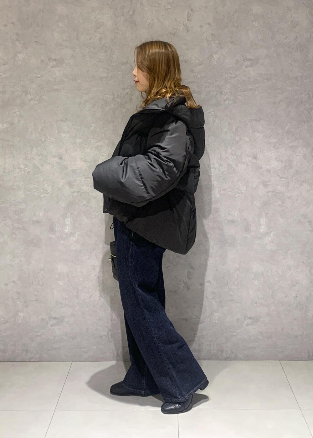 ブラック系のブーツ、ブルー系のデニムパンツ、ブラック系のハンドバッグを着用したレディースの冬コーディネートの4枚目の写真