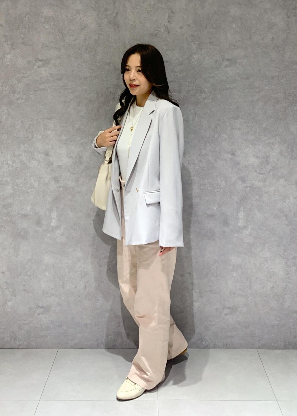 ホワイト系のハンドバッグ、ピンク系のデニムパンツ、ホワイト系のニット/セーターを着用したレディースの冬コーディネートの3枚目の写真