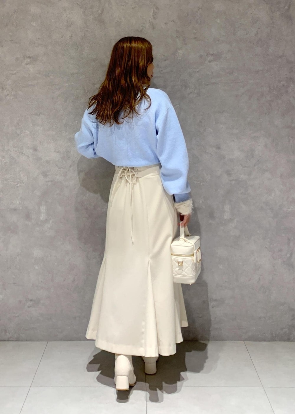 ホワイト系のニット/セーター、ホワイト系のブーツ、ホワイト系のハンドバッグを着用したレディースの冬コーディネートの6枚目の写真