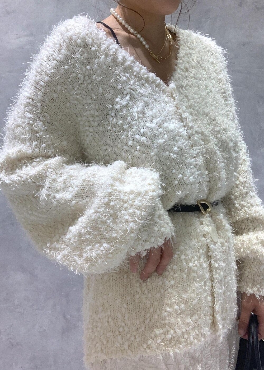 ホワイト系のカーディガン/ボレロ、ブラック系のパンプス、ホワイト系のスカートを着用したレディースの冬コーディネートの8枚目の写真