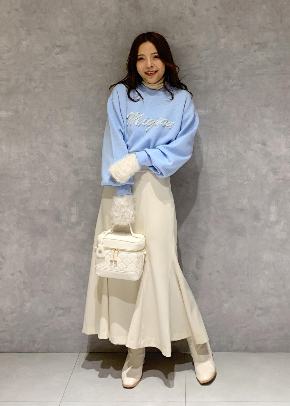 ホワイト系のニット/セーター、ホワイト系のブーツ、ホワイト系のハンドバッグを着用したレディースの冬コーディネートの2枚目の写真