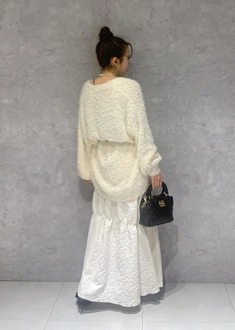 ホワイト系のカーディガン/ボレロ、ブラック系のパンプス、ホワイト系のスカートを着用したレディースの冬コーディネートの6枚目の写真