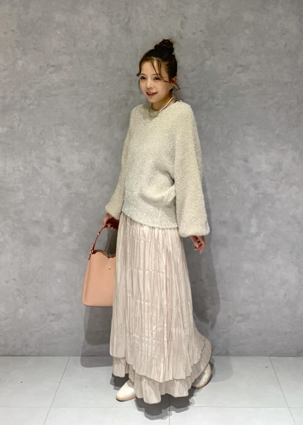 ピンク系のショルダーバッグ、ホワイト系のブーツ、ベージュ系のスカートを着用したレディースの冬コーディネートの3枚目の写真