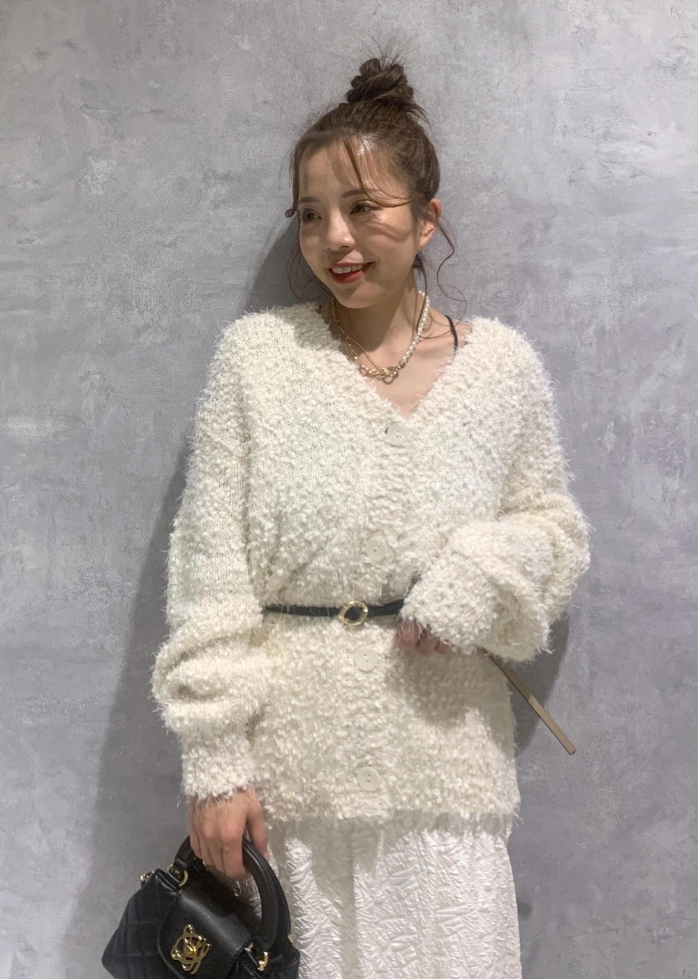 ホワイト系のカーディガン/ボレロ、ブラック系のパンプス、ホワイト系のスカートを着用したレディースの冬コーディネートの7枚目の写真