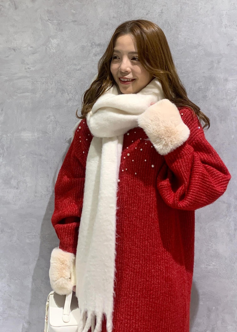 ホワイト系のブーツ、ホワイト系のハンドバッグ、レッド系のワンピースを着用したレディースの冬コーディネートの6枚目の写真