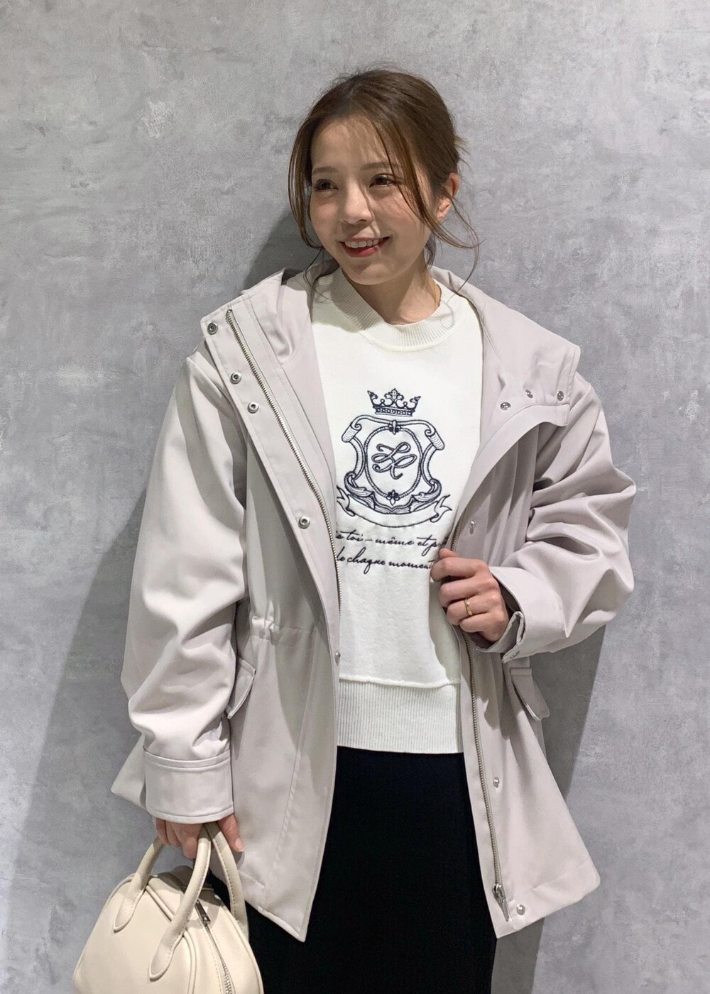 ブラック系のスカート、ベージュ系のボストンバッグ、グレー系のマウンテンパーカーを着用したレディースの春コーディネートの6枚目の写真