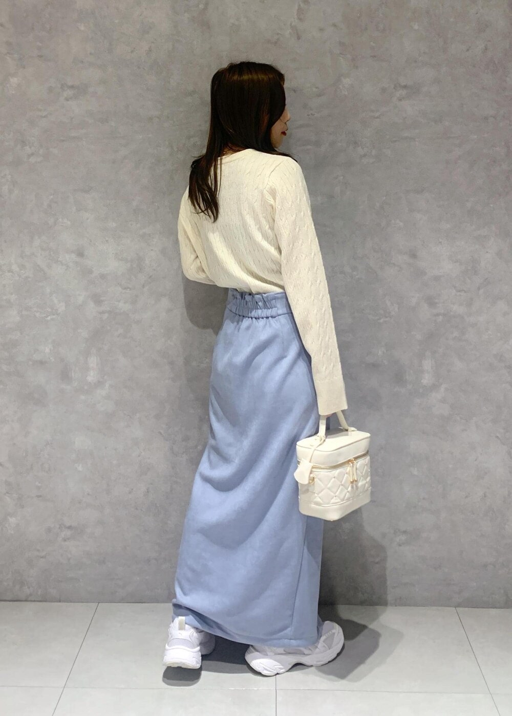 ホワイト系のハンドバッグ、ホワイト系のカーディガン/ボレロ、ブルー系のスカートを着用したレディースの冬コーディネートの6枚目の写真