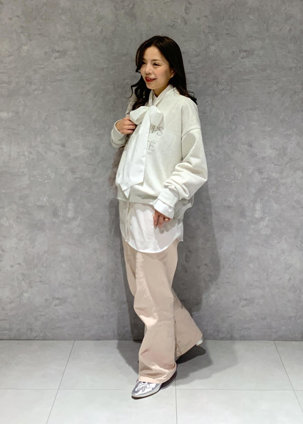 シルバー系のパンプス、ピンク系のデニムパンツ、ベージュ系のショルダーバッグを着用したレディースの冬コーディネートの3枚目の写真