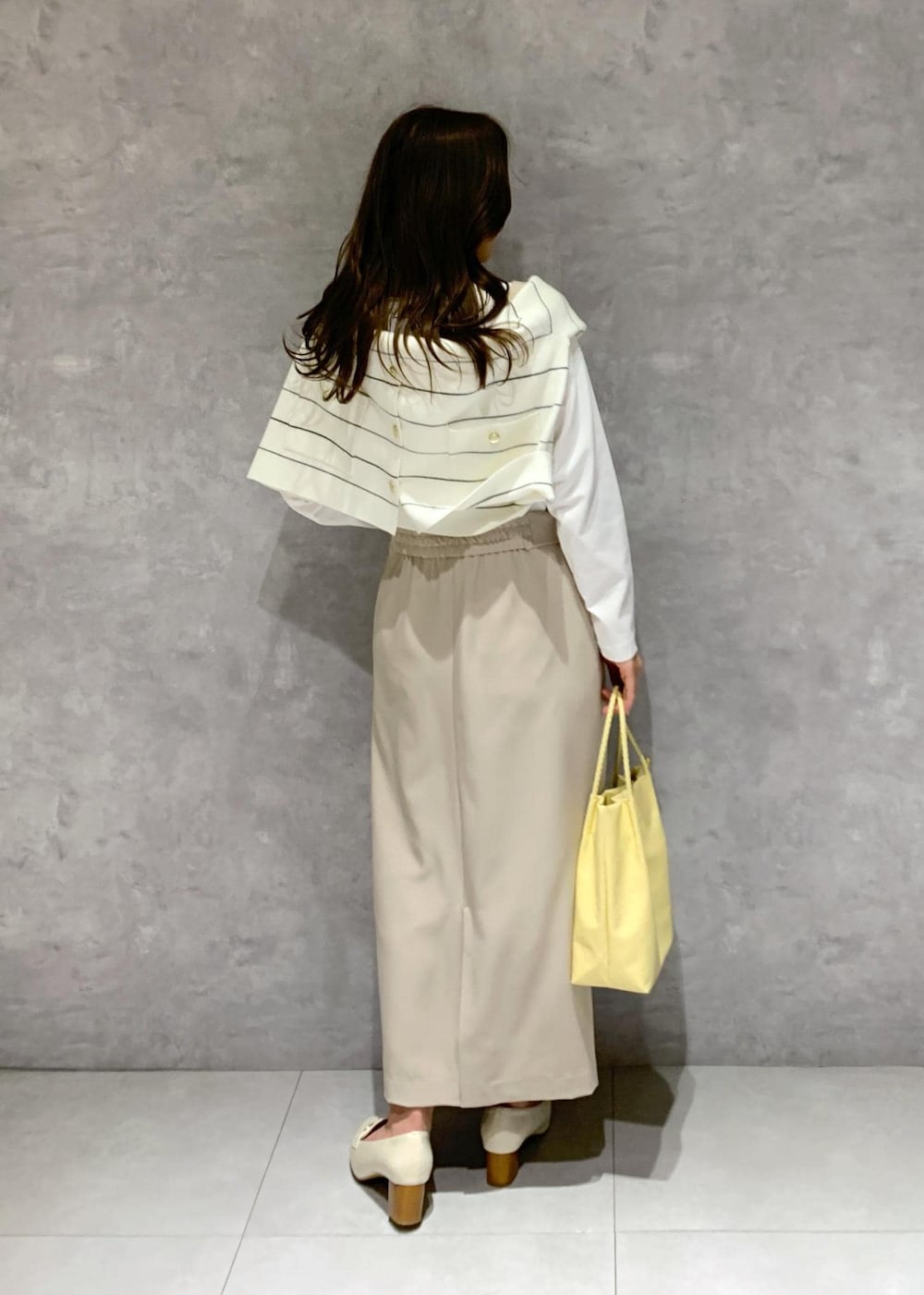 ホワイト系のTシャツ/カットソー、イエロー系のトートバッグ、ベージュ系のジャンパースカートを着用したレディースの冬コーディネートの5枚目の写真