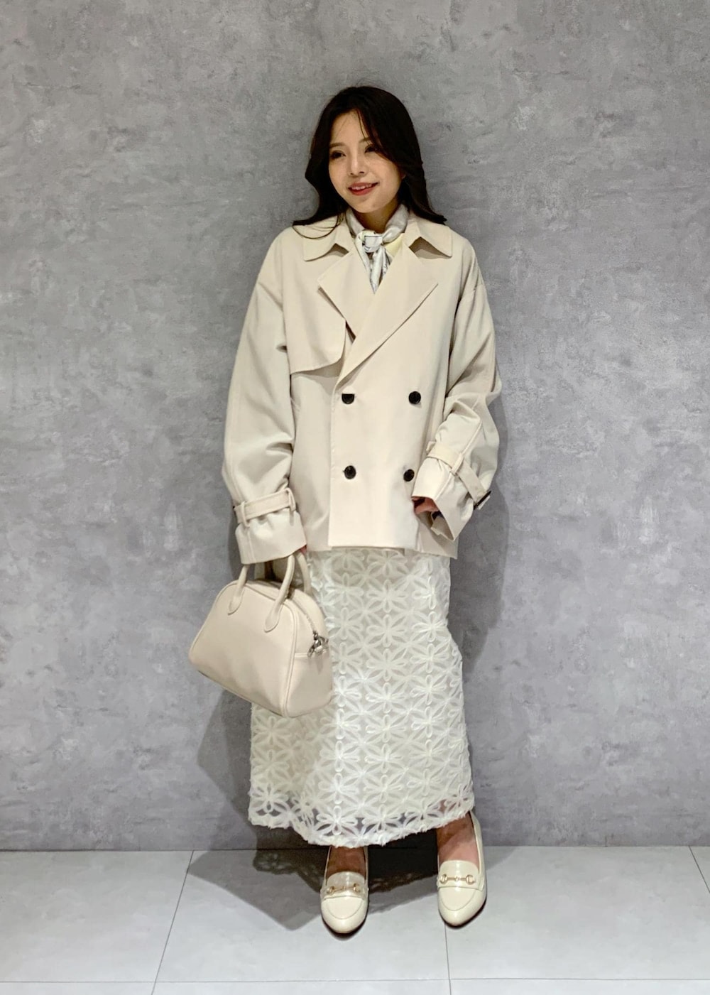 ホワイト系のスカート、ベージュ系のトレンチコート、ベージュ系のニット/セーターを着用したレディースの冬コーディネートの2枚目の写真