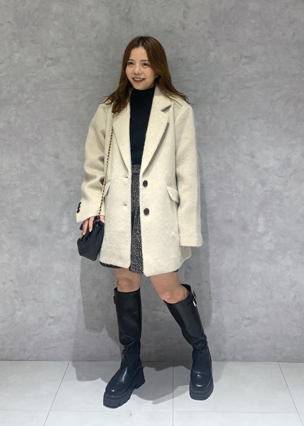 ブラック系のショルダーバッグ、ブラック系のブーツ、ブラック系のニット/セーターを着用したレディースの秋コーディネートの2枚目の写真