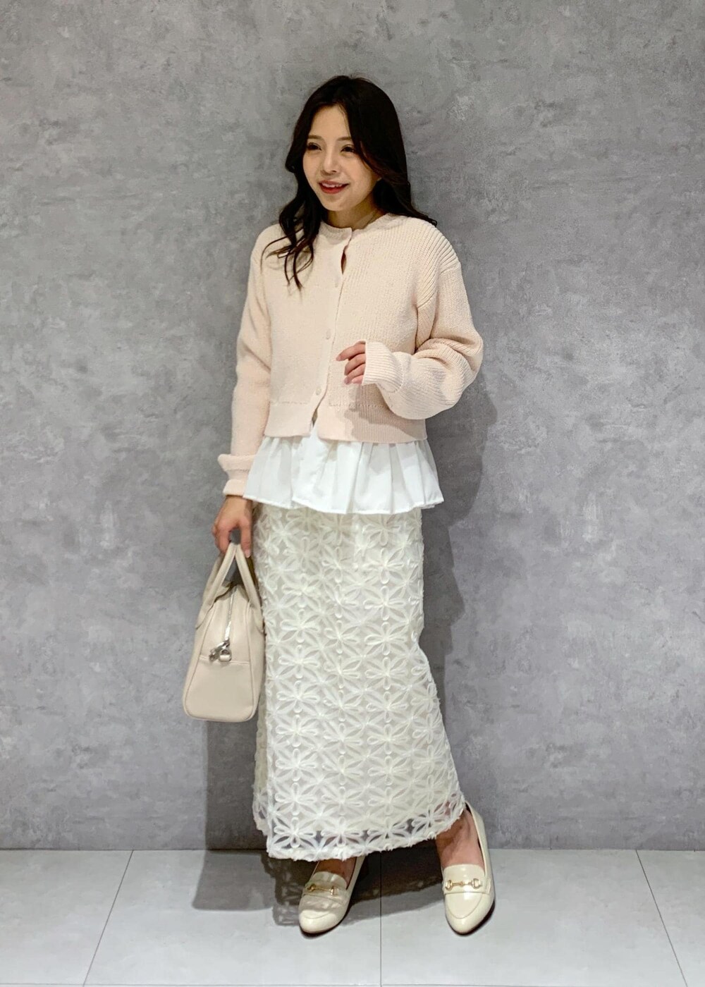 ホワイト系のローファー、ベージュ系のボストンバッグ、ピンク系のカーディガン/ボレロを着用したレディースの冬コーディネートの2枚目の写真