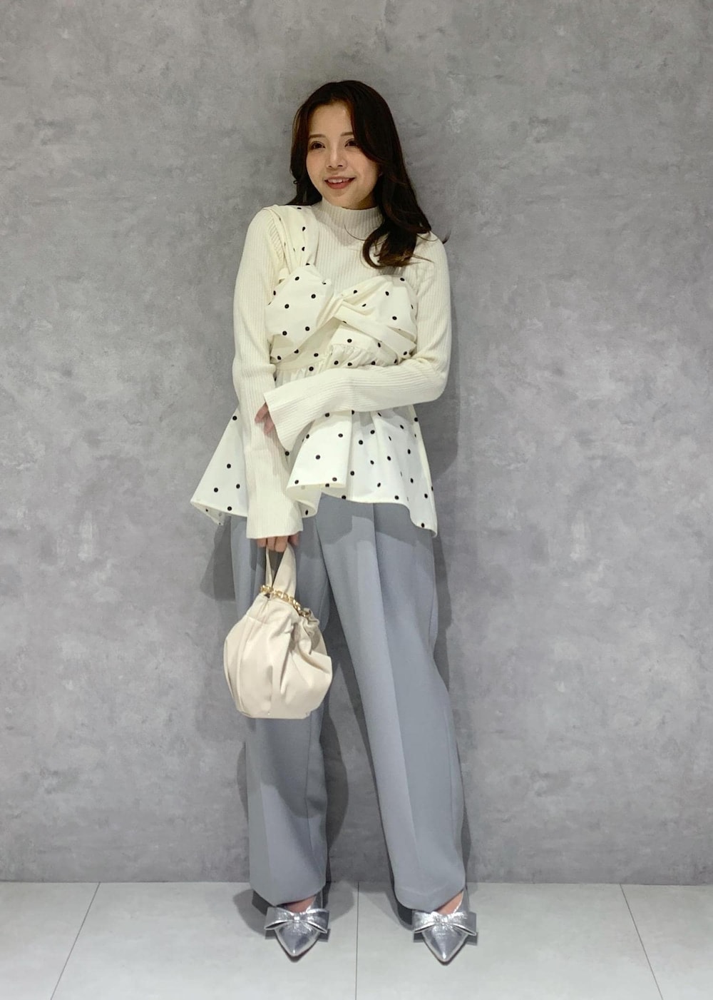 シルバー系のパンプス、ホワイト系のハンドバッグ、ホワイト系のニット/セーターを着用したレディースの冬コーディネートの2枚目の写真
