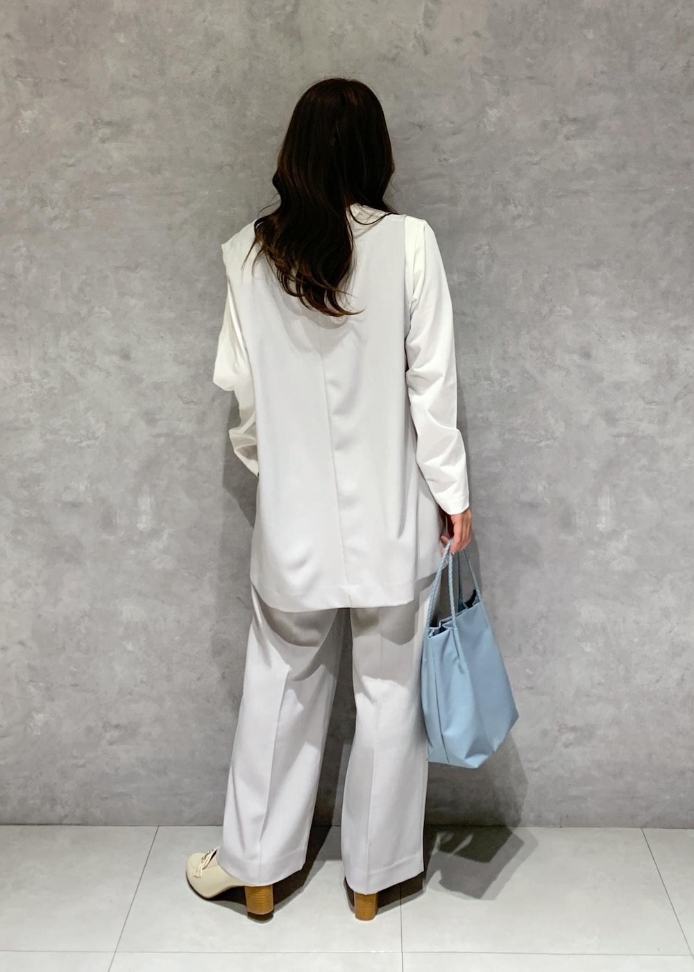 ブルー系のトートバッグ、ホワイト系のTシャツ/カットソー、ホワイト系のローファーを着用したレディースの冬コーディネートの5枚目の写真