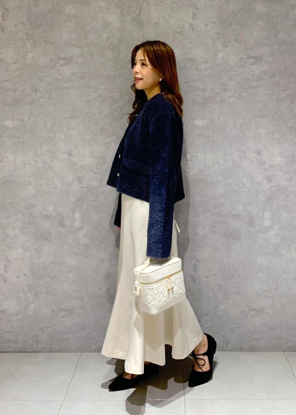 ブルー系のカーディガン/ボレロ、ホワイト系のハンドバッグ、ブラック系のパンプスを着用したレディースの秋コーディネートの3枚目の写真