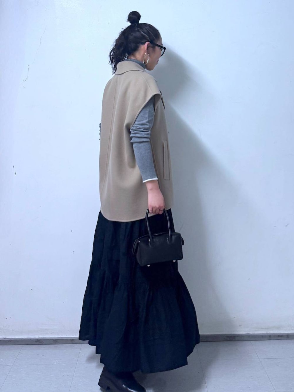 ブラック系のブーツ、ブラック系のハンドバッグ、ブラック系のスカートを着用したレディースの秋コーディネートの2枚目の写真