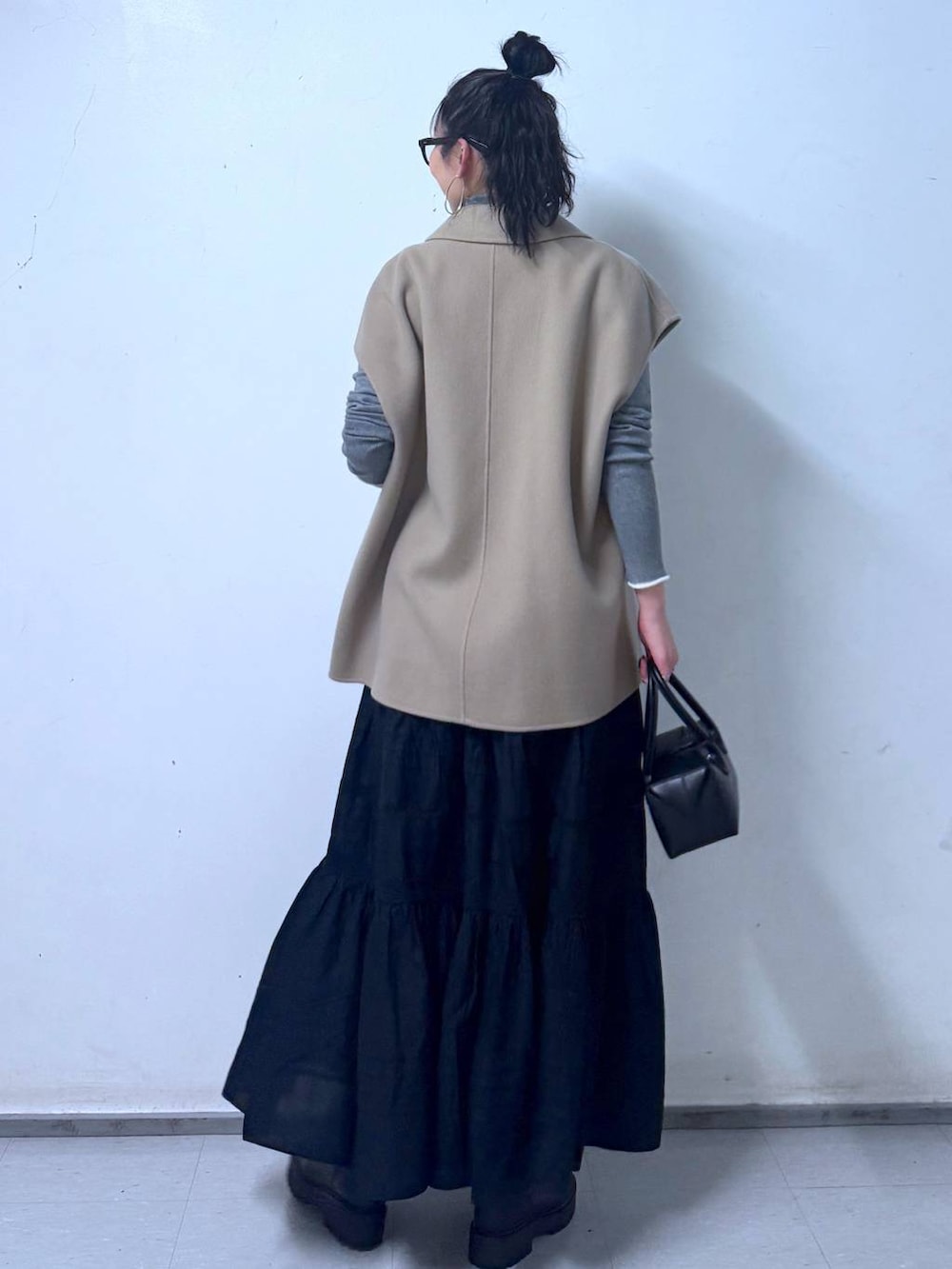 ブラック系のブーツ、ブラック系のハンドバッグ、ブラック系のスカートを着用したレディースの秋コーディネートの3枚目の写真