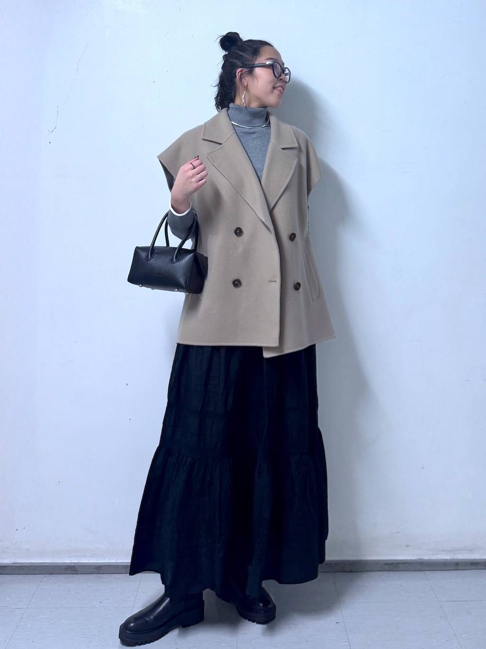 ブラック系のブーツ、ブラック系のハンドバッグ、ブラック系のスカートを着用したレディースの秋コーディネートの4枚目の写真