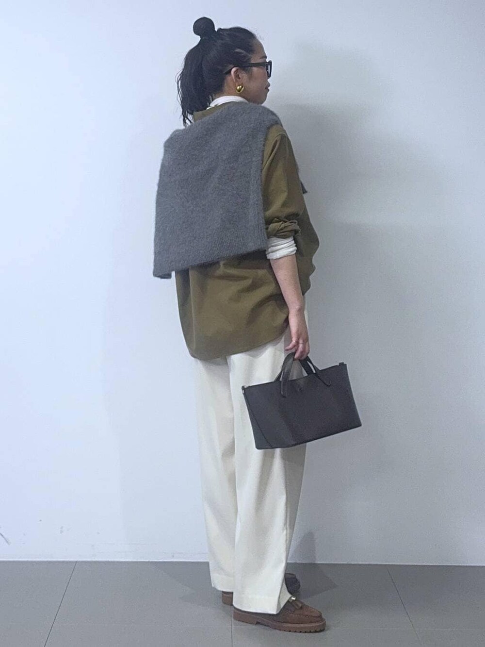 グレー系のニット/セーター、ホワイト系のTシャツ/カットソー、ブラウン系のショルダーバッグを着用したレディースの冬コーディネートの2枚目の写真