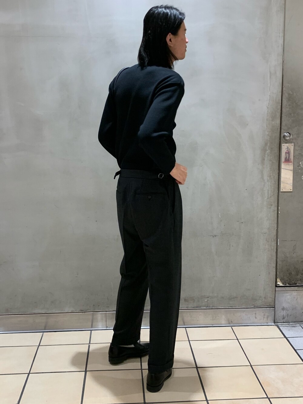 ブラック系のニット/セーター、グレー系のスラックス、ブラック系のショルダーバッグを着用したメンズの冬コーディネートの3枚目の写真