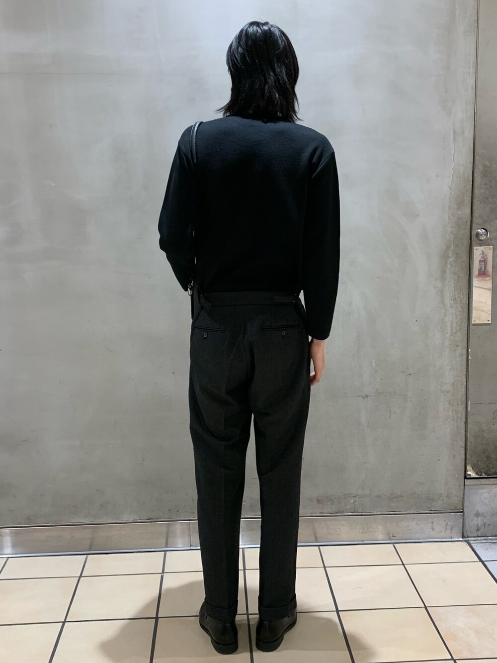 ブラック系のニット/セーター、グレー系のスラックス、ブラック系のショルダーバッグを着用したメンズの冬コーディネートの4枚目の写真