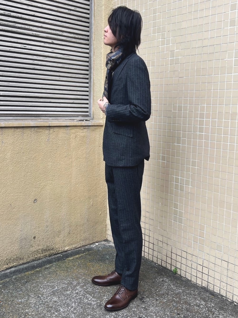 グレー系のスラックス、グレー系のTシャツ/カットソー、グレー系のテーラードジャケットを着用したメンズの冬コーディネートの3枚目の写真