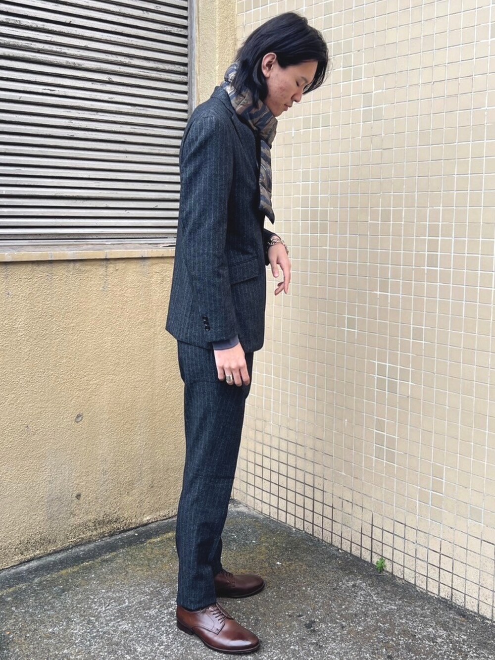 グレー系のスラックス、グレー系のTシャツ/カットソー、グレー系のテーラードジャケットを着用したメンズの冬コーディネートの5枚目の写真