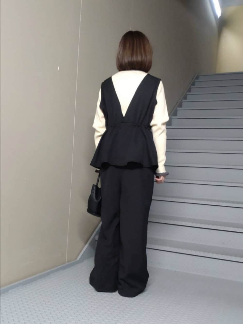 ブラック系のその他パンツ、ホワイト系のニット/セーター、ブラック系のハンドバッグを着用したレディースの冬コーディネートの2枚目の写真