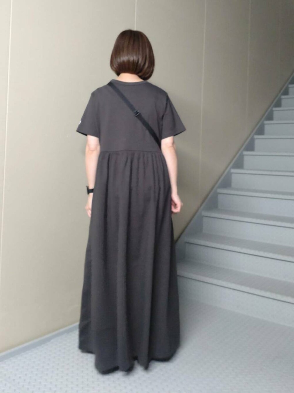 ブルー系のショルダーバッグ、ブラック系のワンピースを着用したレディースの春コーディネートの2枚目の写真