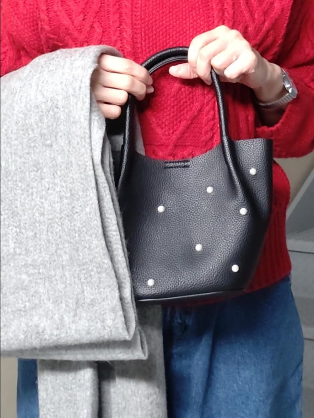 レッド系のニット/セーター、ブルー系のデニムパンツ、ブラック系のハンドバッグを着用したレディースの冬コーディネートの3枚目の写真