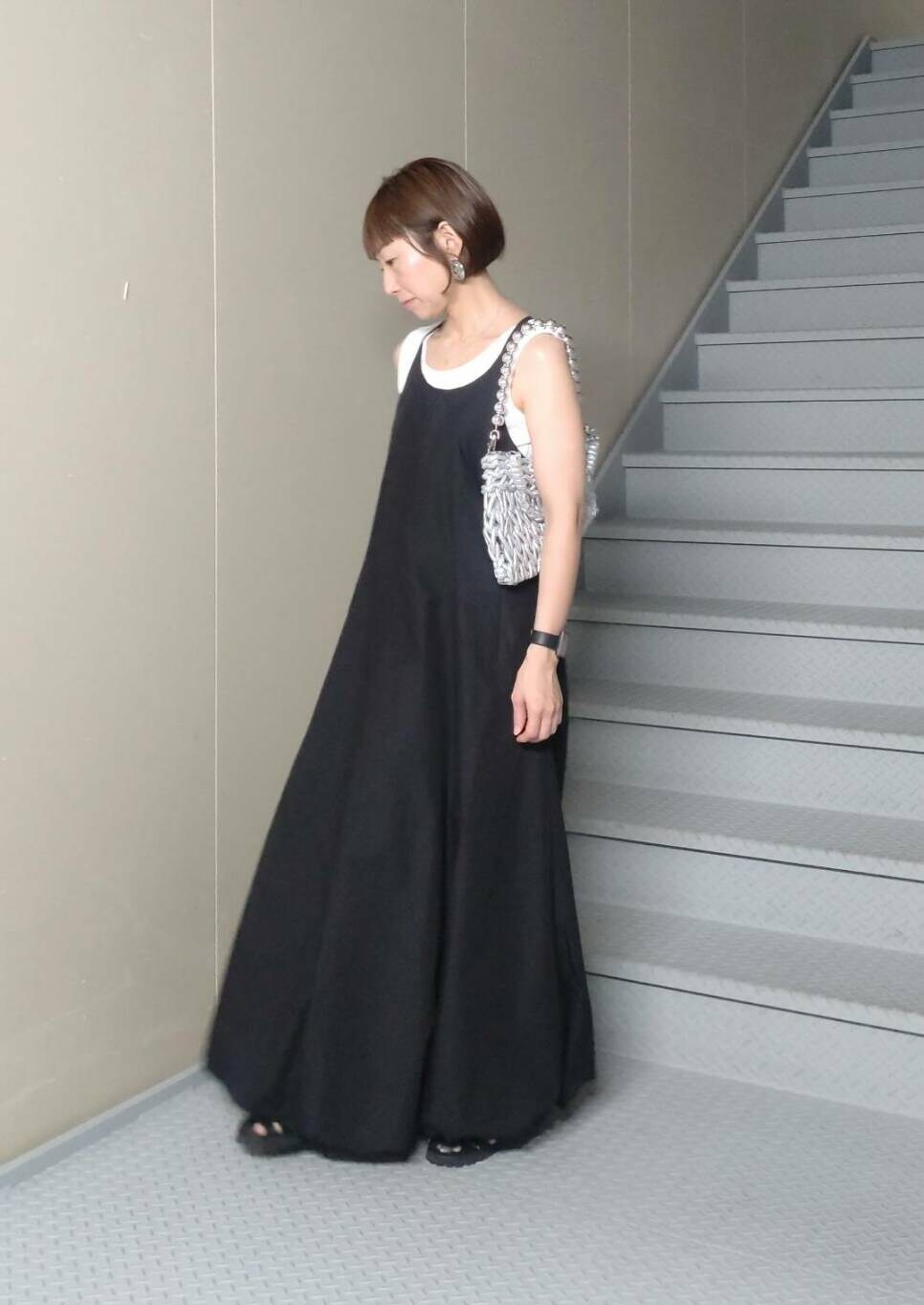 シルバー系のハンドバッグ、ホワイト系のタンクトップ、ブラック系のワンピースを着用したレディースの夏コーディネートの2枚目の写真