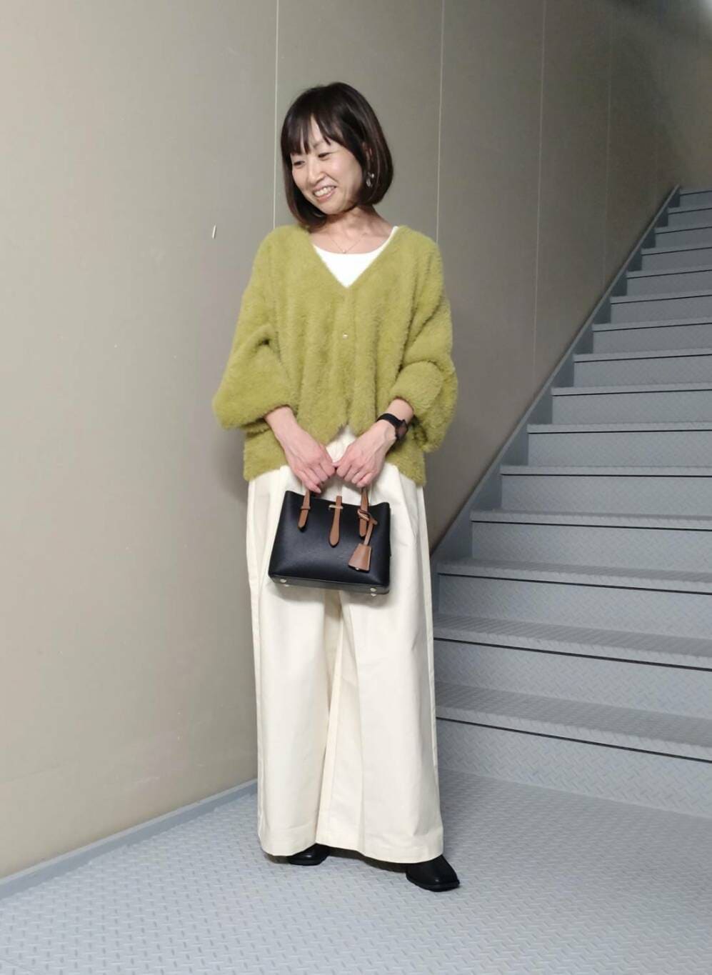 ホワイト系のタンクトップ、グリーン系のカーディガン/ボレロ、ブラック系のブーツを着用したレディースの秋コーディネートの2枚目の写真