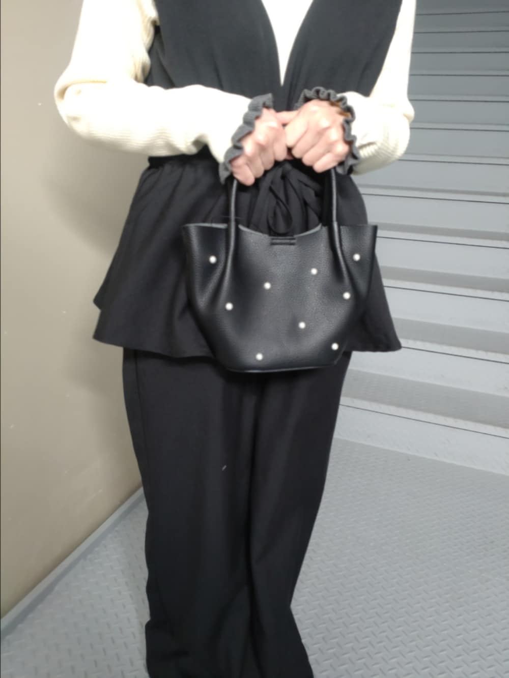 ブラック系のその他パンツ、ホワイト系のニット/セーター、ブラック系のハンドバッグを着用したレディースの冬コーディネートの3枚目の写真