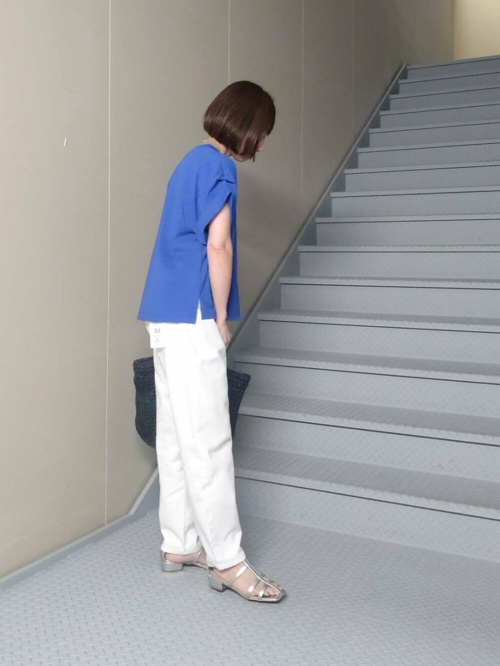 ブラック系のトートバッグ、シルバー系のサンダル、ホワイト系のデニムパンツを着用したレディースの夏コーディネートの3枚目の写真