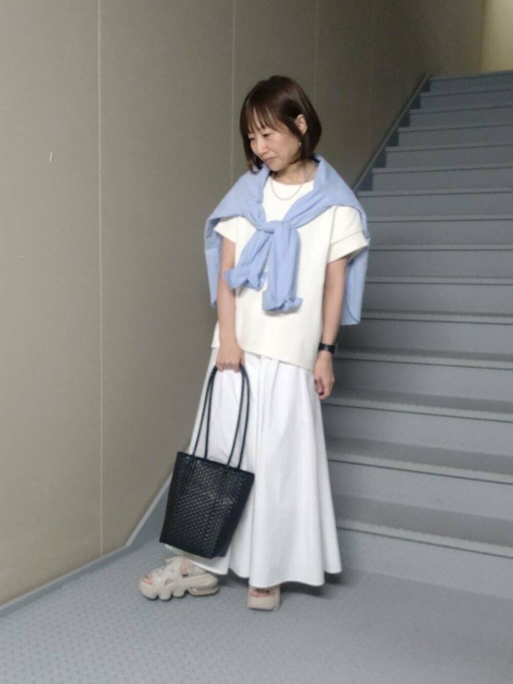 ホワイト系のスカート、ブルー系のシャツ/ブラウス、ブラック系のトートバッグを着用したレディースの春コーディネートの2枚目の写真