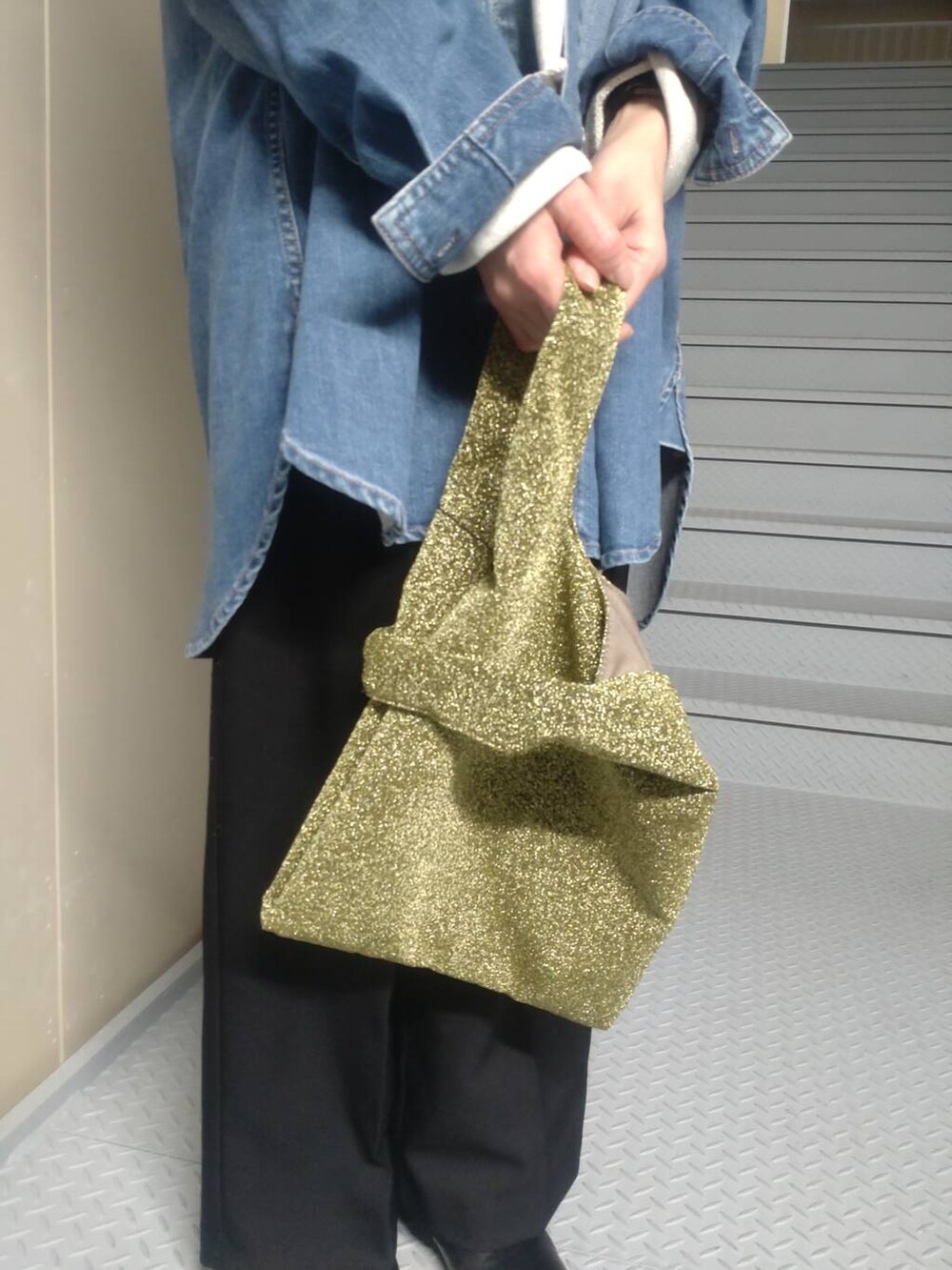 ゴールド系のトートバッグ、ブルー系のシャツ/ブラウス、ベージュ系のスウェットを着用したレディースの冬コーディネートの3枚目の写真