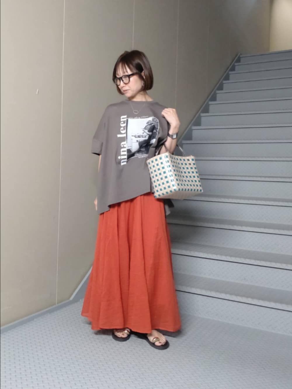 グレー系のTシャツ/カットソー、レッド系のスカート、ブラウン系のサンダルを着用したレディースの夏コーディネートの2枚目の写真