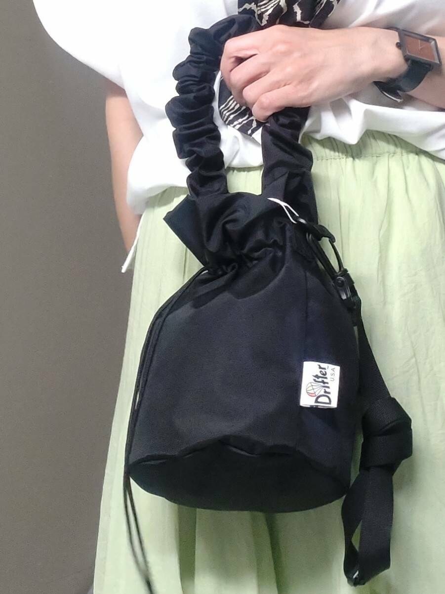 ブラック系のショルダーバッグ、ブラック系のサンダル、グリーン系のスカートを着用したレディースの夏コーディネートの3枚目の写真