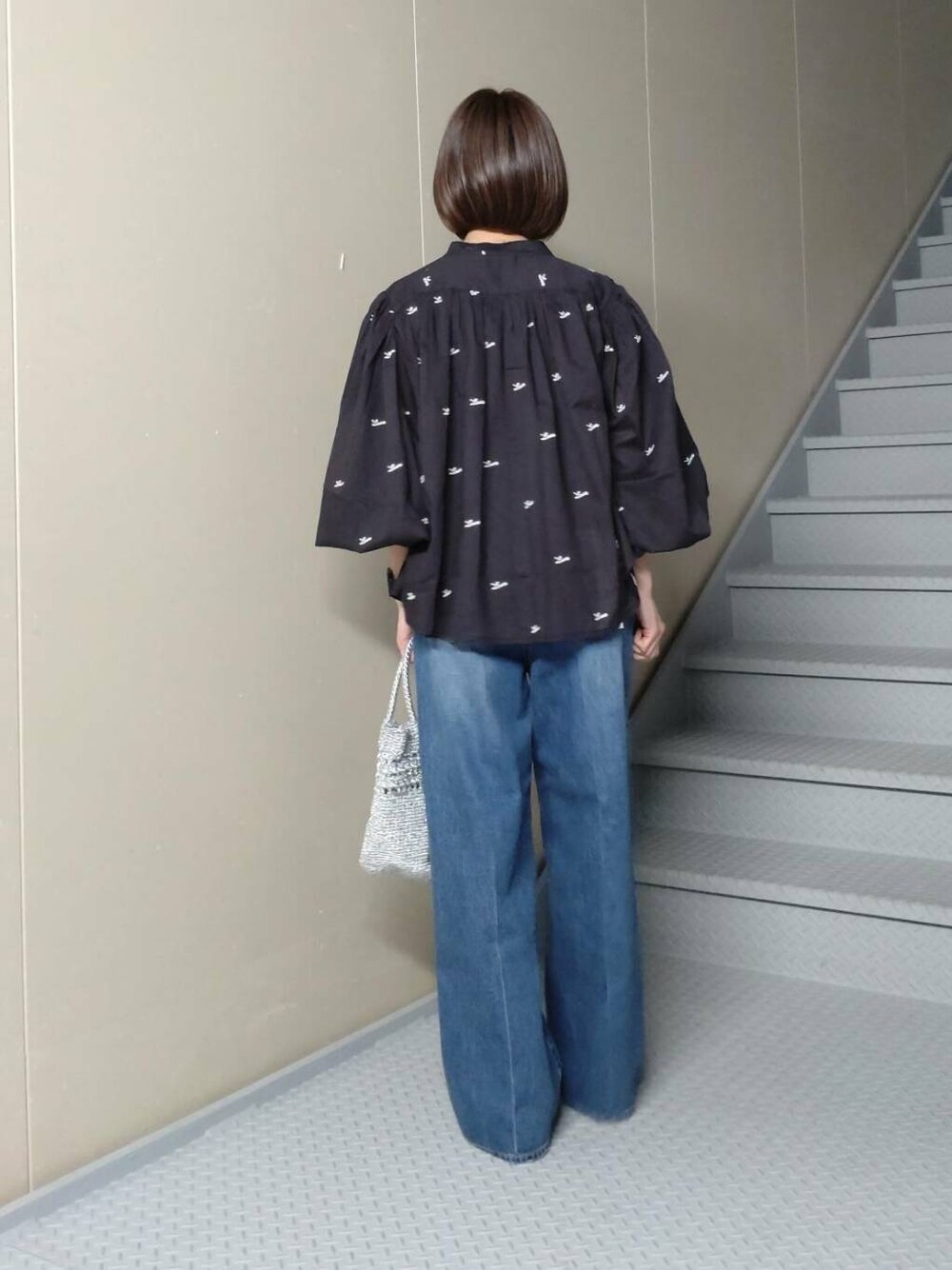 シルバー系のショルダーバッグ、ブルー系のデニムパンツ、ブラック系のシャツ/ブラウスを着用したレディースの春コーディネートの2枚目の写真