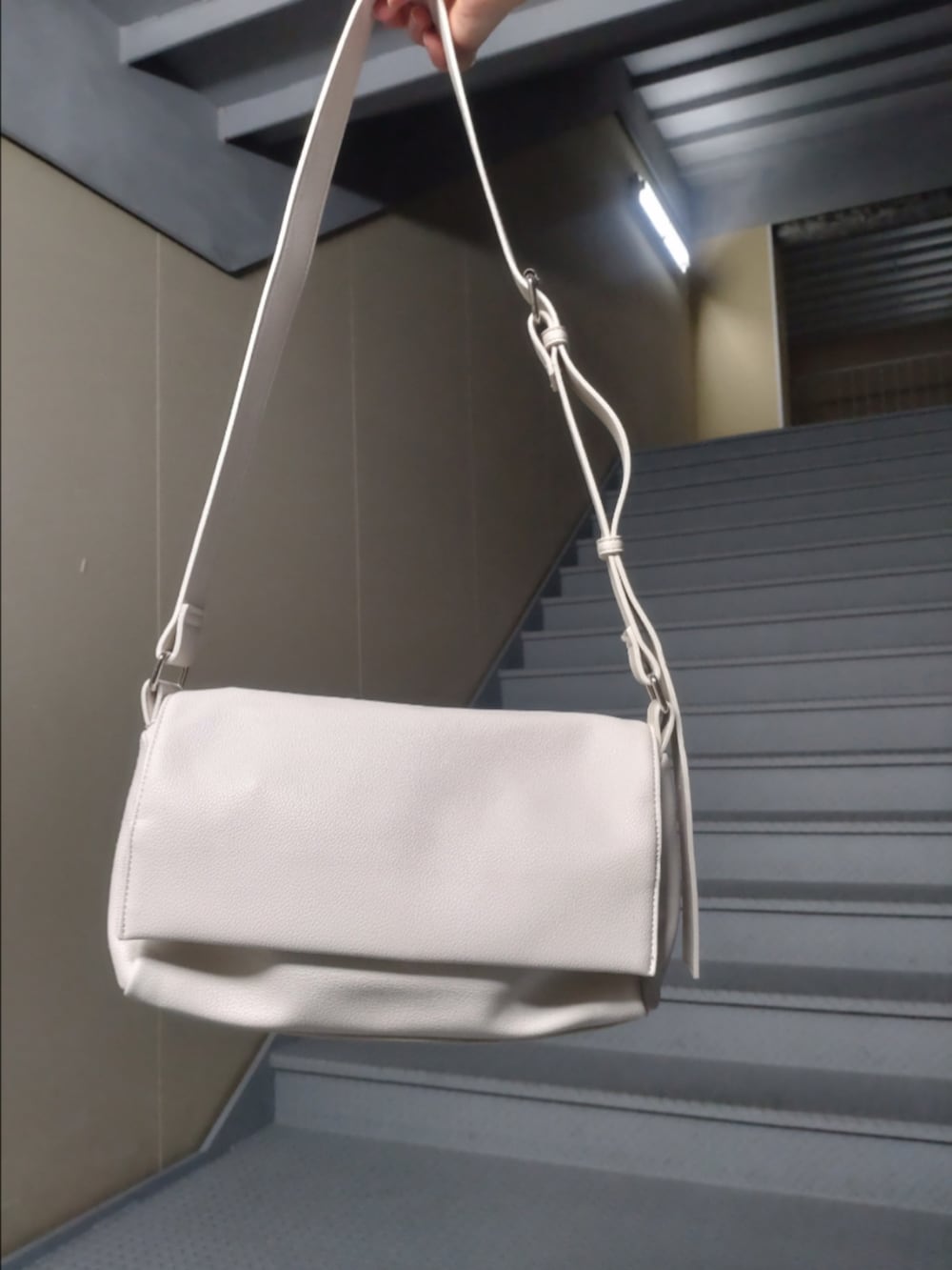 ブルー系のジャンパースカート、ブラウン系のニット/セーター、ホワイト系のショルダーバッグを着用したレディースの秋コーディネートの3枚目の写真