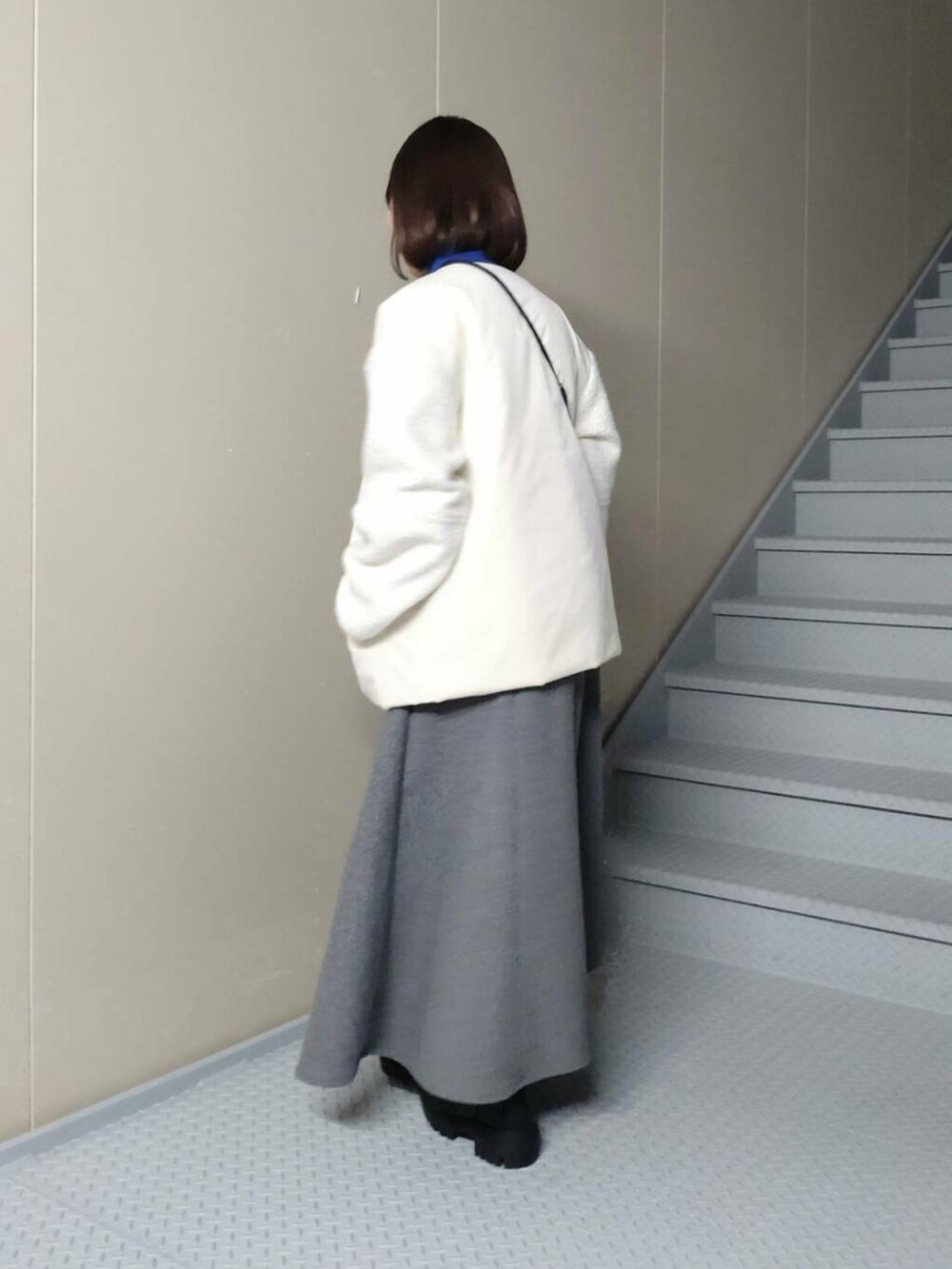 ブラック系のブーツ、ホワイト系のブルゾン、ブルー系のニット/セーターを着用したレディースの冬コーディネートの2枚目の写真