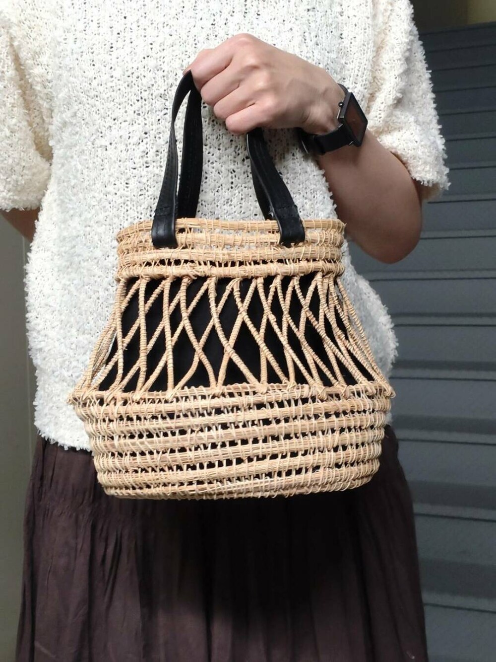 ブラウン系のスカート、ホワイト系のニット/セーター、ブラック系のかごバッグを着用したレディースの春コーディネートの3枚目の写真